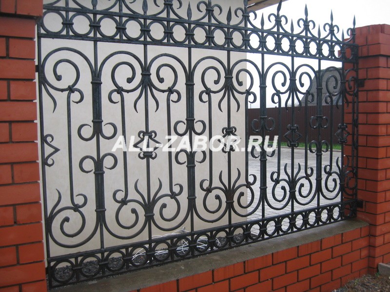 Кованый забор черного цвета с фундаментом и столбами из кирпича